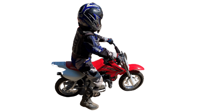 A 7 year old boy with safety gear on a Honda 50cc dirt bike ready to speed