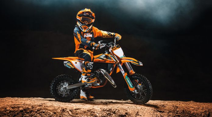 Man sitting on the KTM 50 SX Factory Edition dirt bike with black background