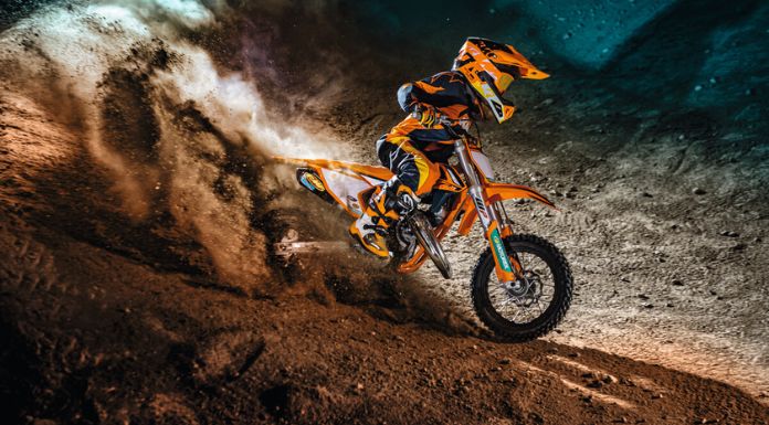 Side view image of kid riding on his KTM 50 SX Factory Edition dirt bike leaving dust.