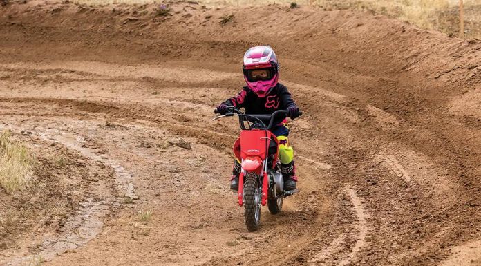 A boy kid riding a Honda CRF50F dirt bike.