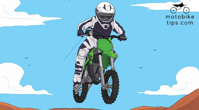 Young rider on a motocross track jumping off his Kawasaki kx65 dirt bike with beautiful blue sky.