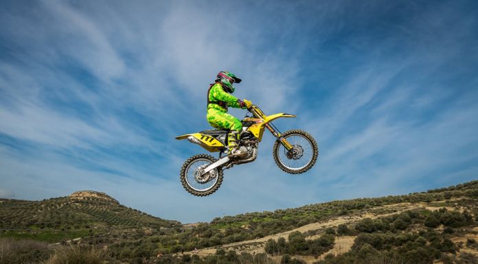 Man jumping off his suzuki rm85 dirt bike with beautiful sky at the back